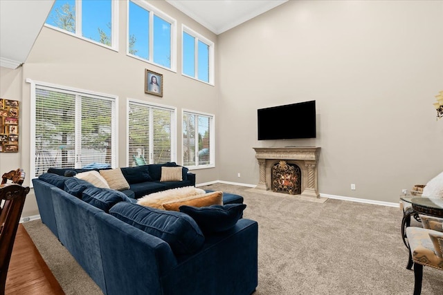 carpeted living room featuring crown molding, baseboards, a towering ceiling, and a fireplace