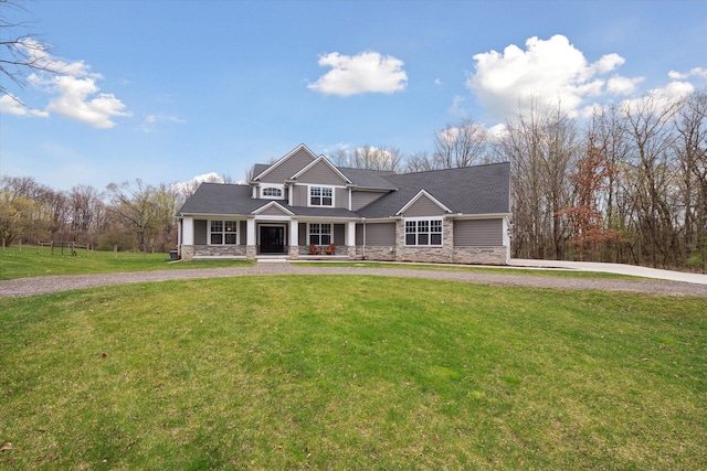 craftsman inspired home featuring a porch, curved driveway, stone siding, and a front lawn