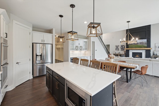 kitchen with white cabinets, an inviting chandelier, dark wood finished floors, stainless steel appliances, and a kitchen island