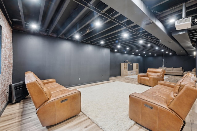 home theater featuring visible vents, wood finished floors, and brick wall
