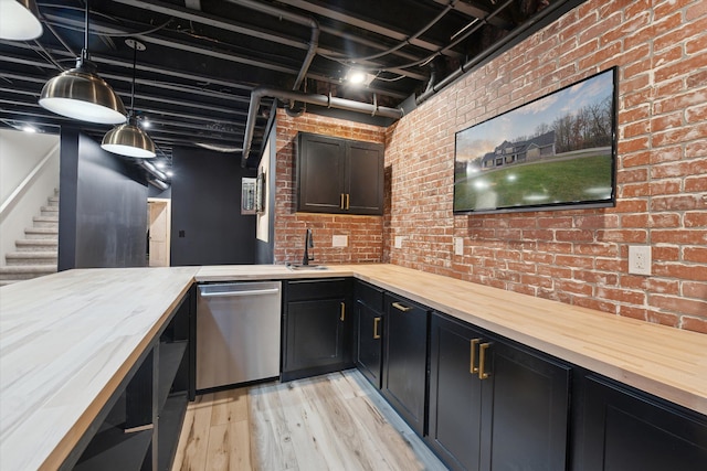 bar featuring brick wall, pendant lighting, stainless steel dishwasher, a sink, and light wood finished floors