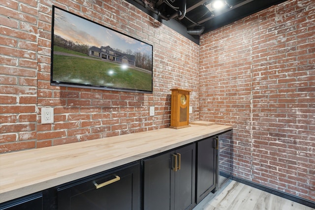 bar with brick wall and light wood finished floors