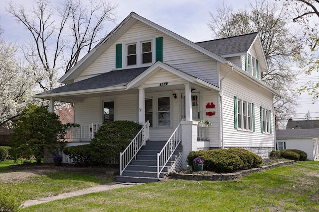 bungalow-style house with a porch, a shingled roof, and a front lawn