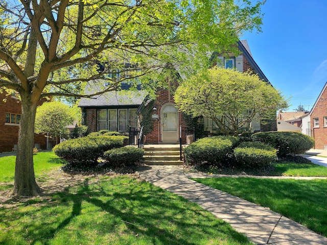 obstructed view of property featuring a front yard and brick siding