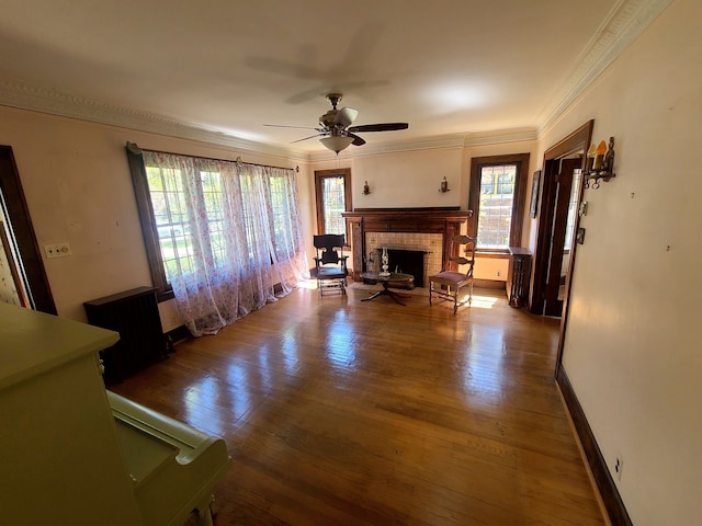living room with a healthy amount of sunlight, wood finished floors, a ceiling fan, and crown molding