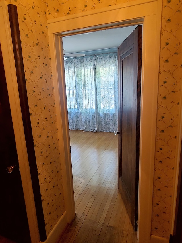 hallway with wood-type flooring and wallpapered walls