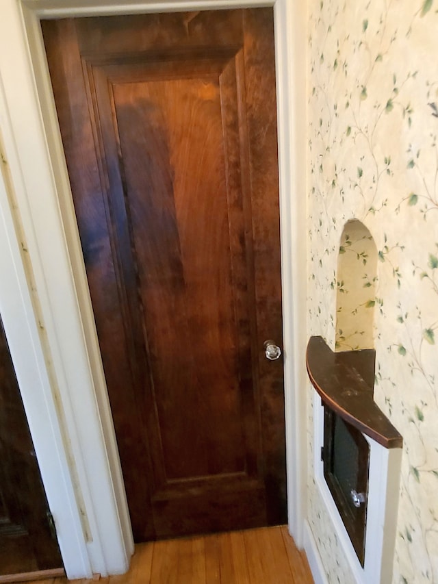 interior space with wallpapered walls and wood finished floors