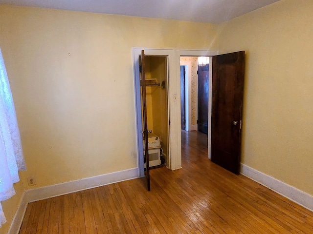 unfurnished bedroom with hardwood / wood-style flooring and baseboards