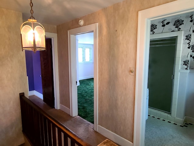 corridor featuring tile patterned flooring, a chandelier, and baseboards