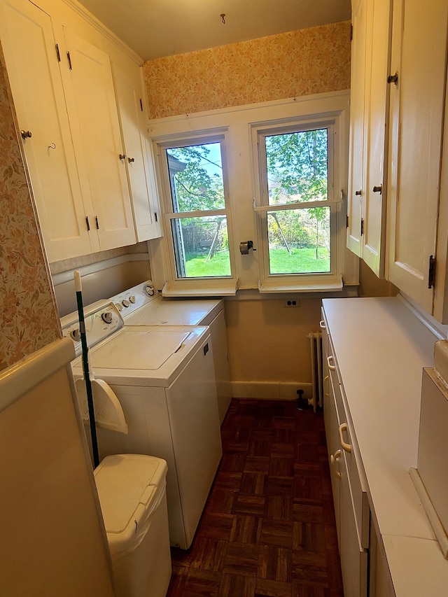 clothes washing area with radiator, baseboards, washer and dryer, and cabinet space