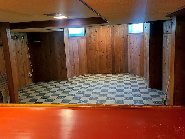 below grade area featuring wood walls, a wealth of natural light, and tile patterned floors