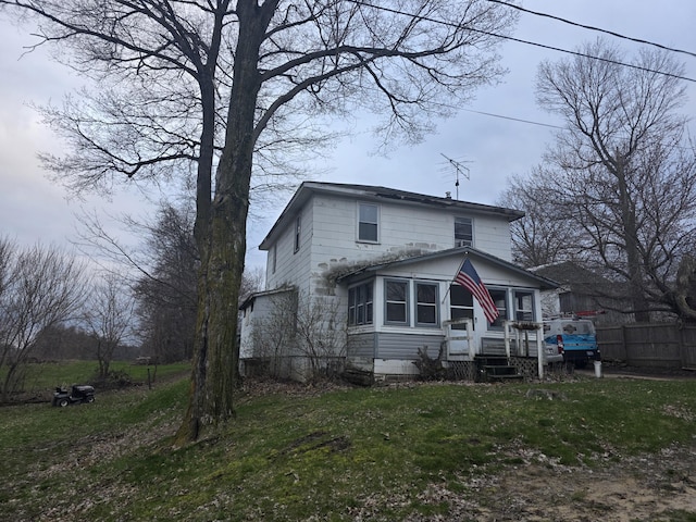 view of front facade featuring fence, a front lawn, and a sunroom