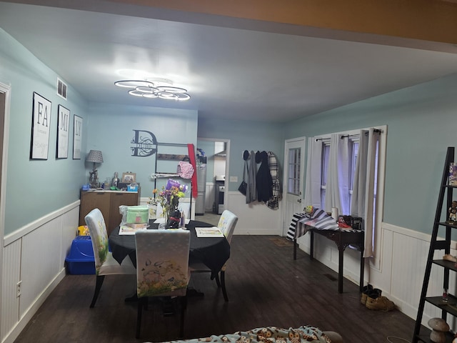 dining room featuring dark wood-style flooring, wainscoting, and visible vents