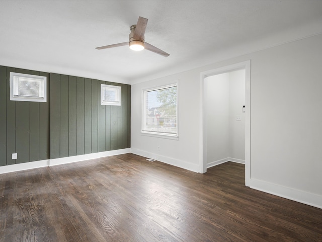 22625 Oaklane St, Warren, MI 48089 - unfurnished room featuring baseboards, wooden walls, ceiling fan, and dark wood-style floors