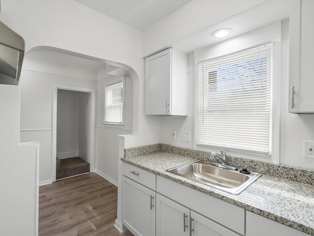 22625 Oaklane St, Warren, MI 48089 - kitchen with dark wood-style flooring, baseboards, arched walkways, white cabinets, and a sink