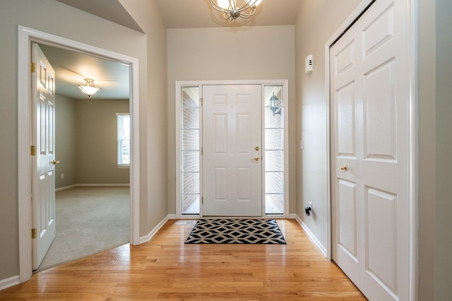 foyer entrance featuring baseboards, a chandelier, and light wood finished floors