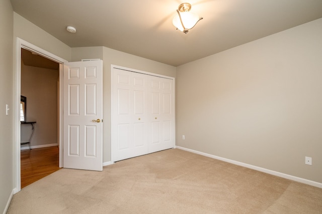 unfurnished bedroom featuring baseboards, a closet, and light colored carpet