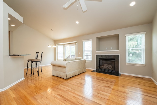living area with plenty of natural light, light wood-style floors, vaulted ceiling, and a fireplace