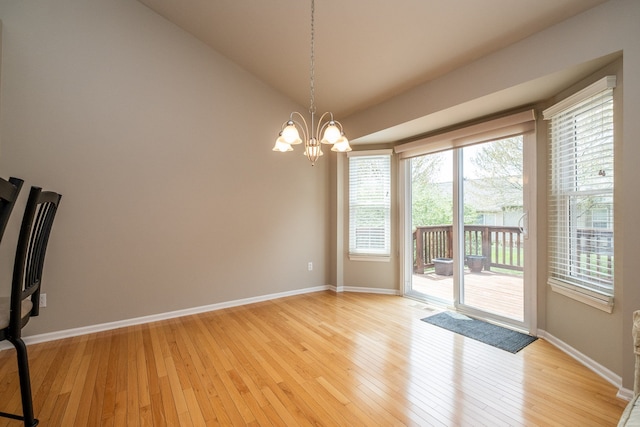 unfurnished dining area with baseboards, an inviting chandelier, vaulted ceiling, and light wood-type flooring