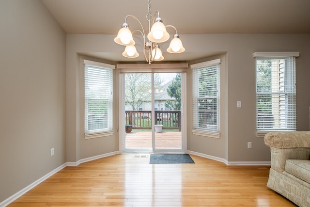 doorway to outside with baseboards, visible vents, light wood-type flooring, and a chandelier