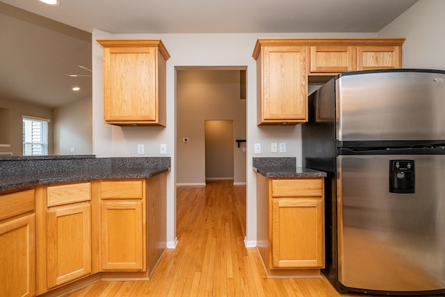 kitchen featuring baseboards, freestanding refrigerator, light wood finished floors, dark stone counters, and recessed lighting