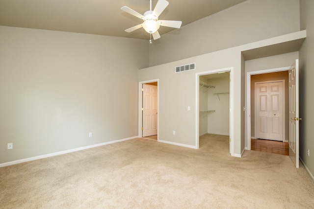 unfurnished bedroom featuring visible vents, baseboards, a spacious closet, and light carpet