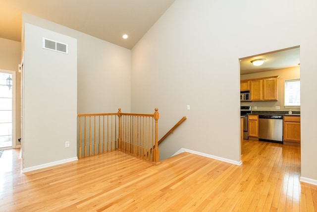 interior space with a high ceiling, hardwood / wood-style floors, recessed lighting, baseboards, and visible vents