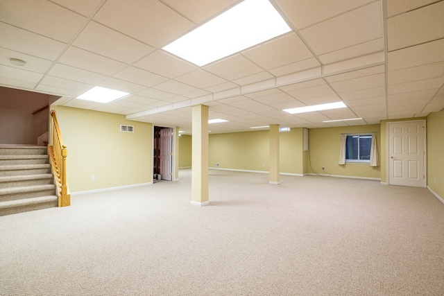finished below grade area featuring carpet floors, baseboards, visible vents, and stairway