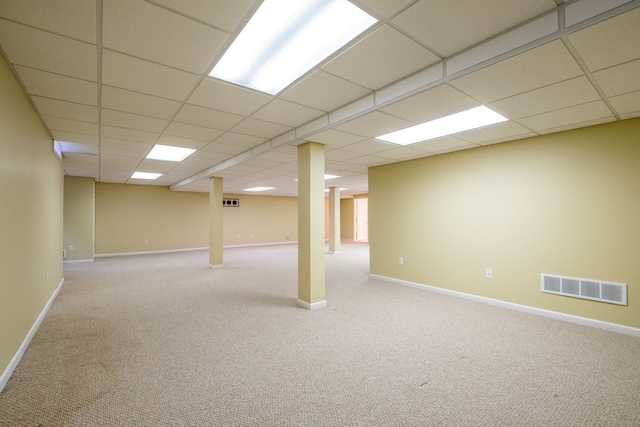 finished basement with carpet floors, baseboards, a drop ceiling, and visible vents