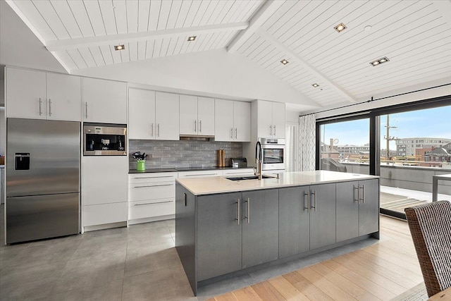 kitchen with gray cabinets, backsplash, a sink, vaulted ceiling with beams, and stainless steel appliances
