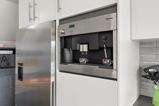 kitchen featuring stainless steel fridge with ice dispenser, backsplash, and white cabinetry