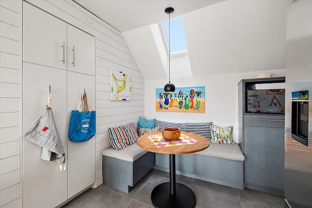 interior space featuring wooden walls, lofted ceiling with skylight, and breakfast area