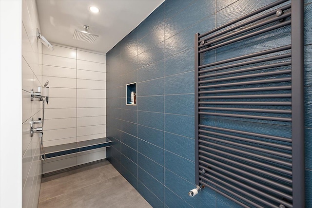 bathroom featuring radiator, tile walls, concrete floors, and tiled shower