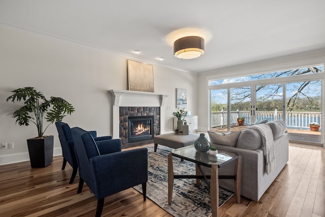 5027 Grover Dr, Brighton, MI 48116 - living area featuring wood finished floors, crown molding, a water view, baseboards, and a tile fireplace