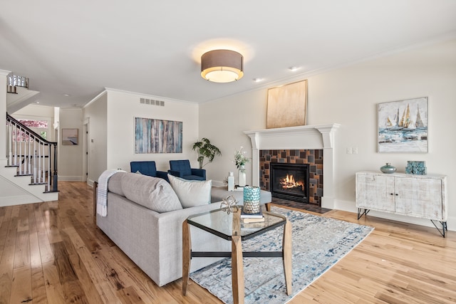 5027 Grover Dr, Brighton, MI 48116 - living room featuring wood finished floors, ornamental molding, visible vents, stairway, and a fireplace with flush hearth