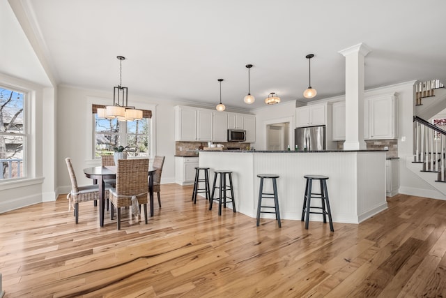 5027 Grover Dr, Brighton, MI 48116 - kitchen with a breakfast bar, dark countertops, stainless steel appliances, light wood-style floors, and tasteful backsplash