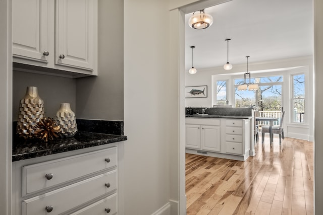 5027 Grover Dr, Brighton, MI 48116 - bar with hanging light fixtures, an inviting chandelier, a sink, visible vents, and light wood-style floors