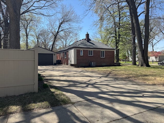 21260 Kipling St, Oak Park, MI 48237 - view of property exterior featuring a chimney, driveway, brick siding, an outdoor structure, and central air condition unit