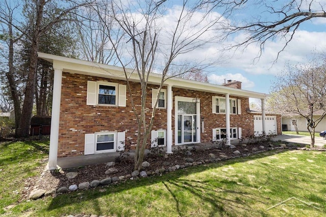 raised ranch featuring brick siding, a front lawn, a chimney, and concrete driveway