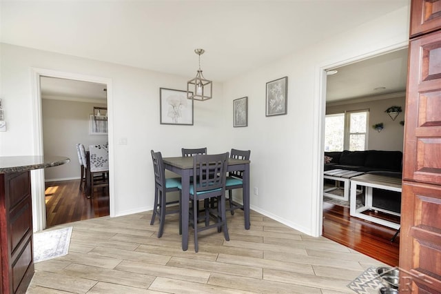 dining area with crown molding, baseboards, a chandelier, and light wood-type flooring