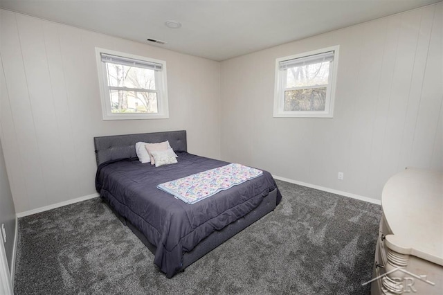 carpeted bedroom featuring baseboards, visible vents, and multiple windows