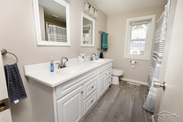full bath with double vanity, baseboards, a sink, and wood finished floors