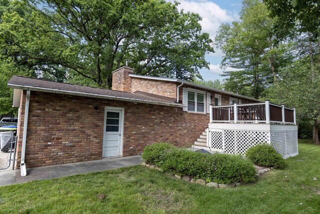 411 Rollcrest Ct, Midland, MI 48640 - back of house with a lawn, a chimney, brick siding, and a deck