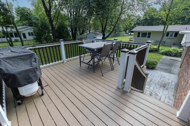 411 Rollcrest Ct, Midland, MI 48640 - deck with outdoor dining space, a storage unit, a fenced backyard, grilling area, and view of scattered trees