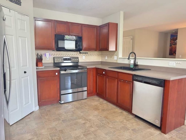 kitchen with a peninsula, light countertops, tasteful backsplash, a sink, and stainless steel appliances