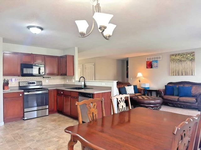kitchen with a sink, a peninsula, black microwave, open floor plan, and electric stove