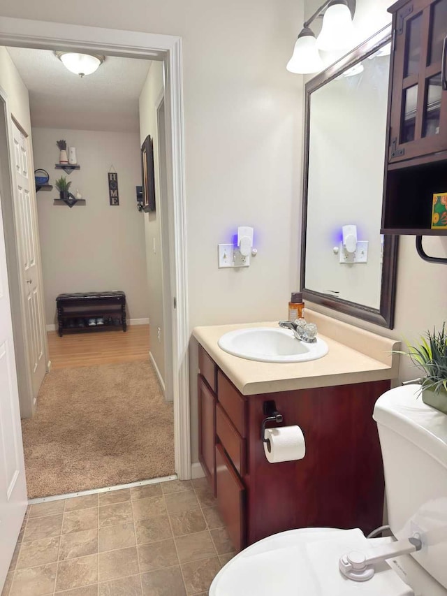 half bathroom featuring vanity, baseboards, and toilet