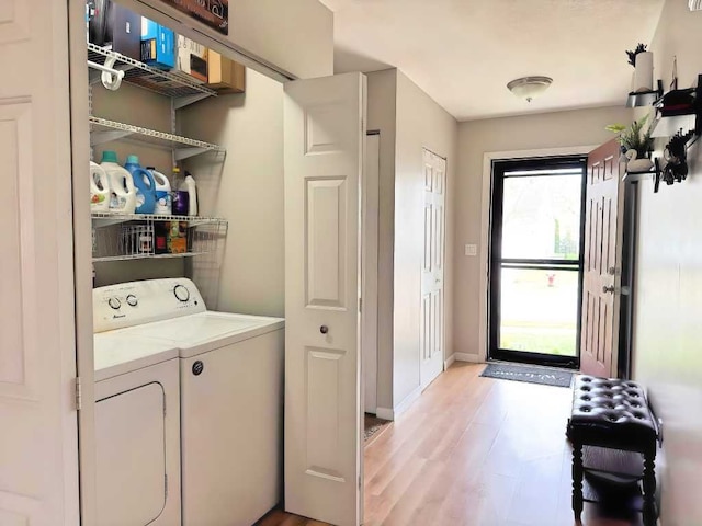 clothes washing area with washing machine and clothes dryer, laundry area, baseboards, and light wood-type flooring