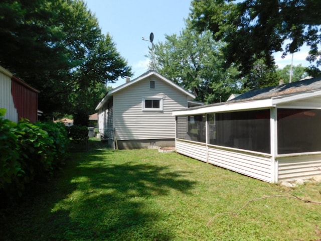 rear view of house featuring a lawn, fence, and a sunroom