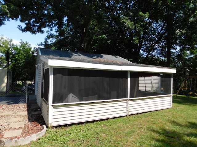 view of side of home with fence, a yard, a sunroom, and a playground